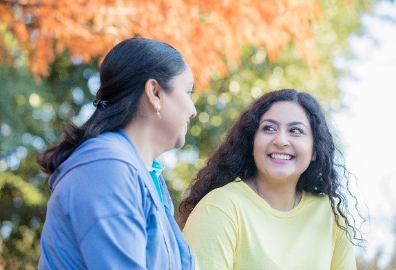 Une adolescente souriante est assise à côté d’une adulte